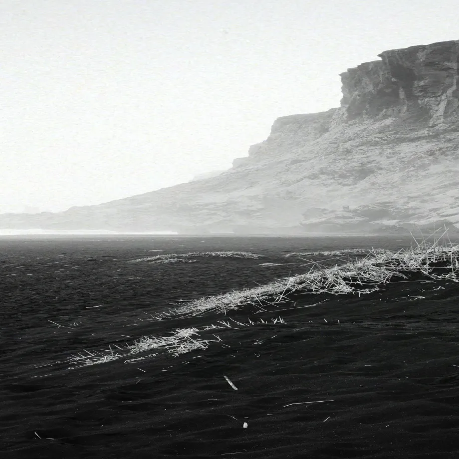 A black and white photo of a mountain with a river in the foreground.